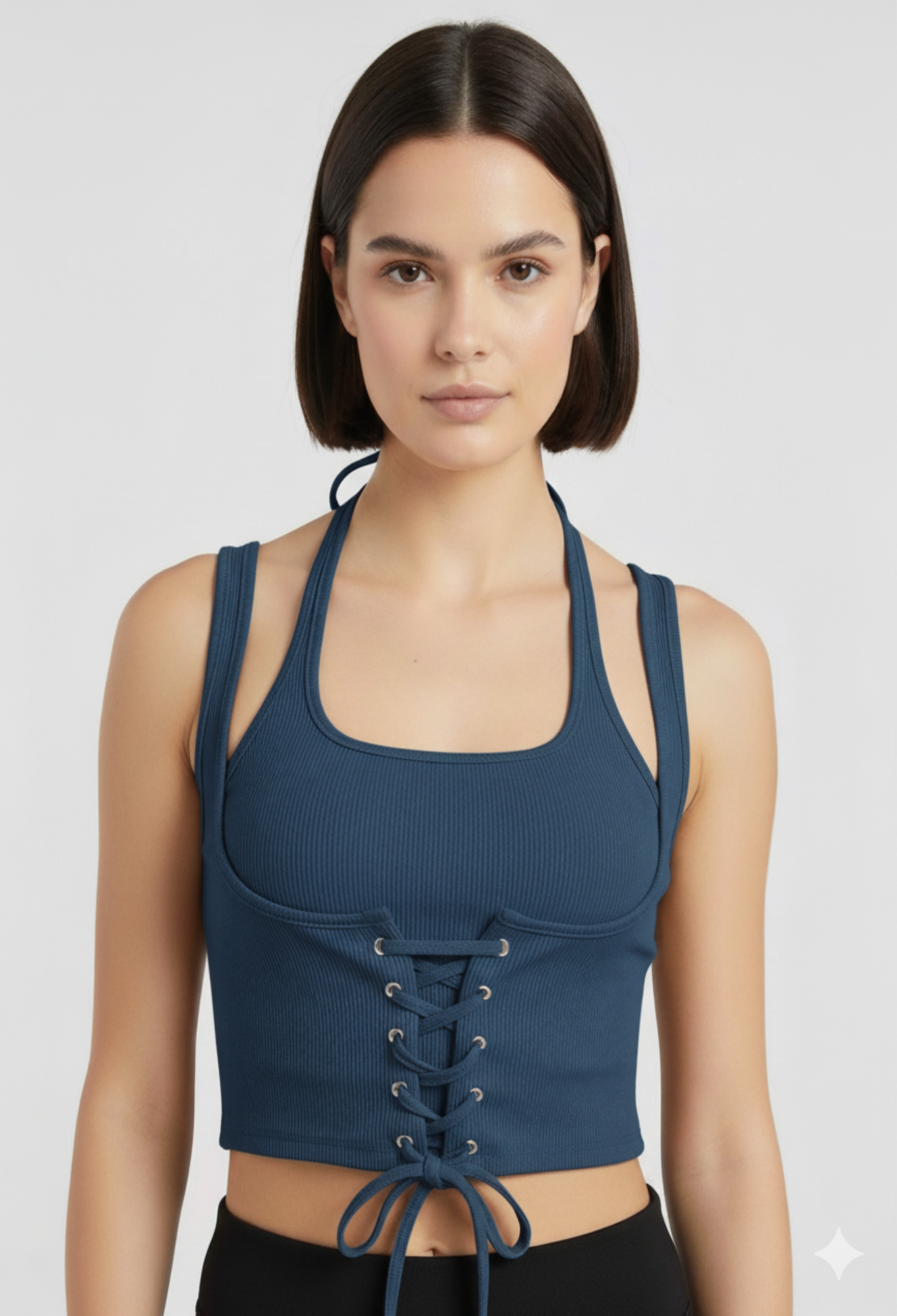 Close-up of a female model wearing a fitted blue ribbed halter crop top with a corset-style lace-up front and a tie at the hem.