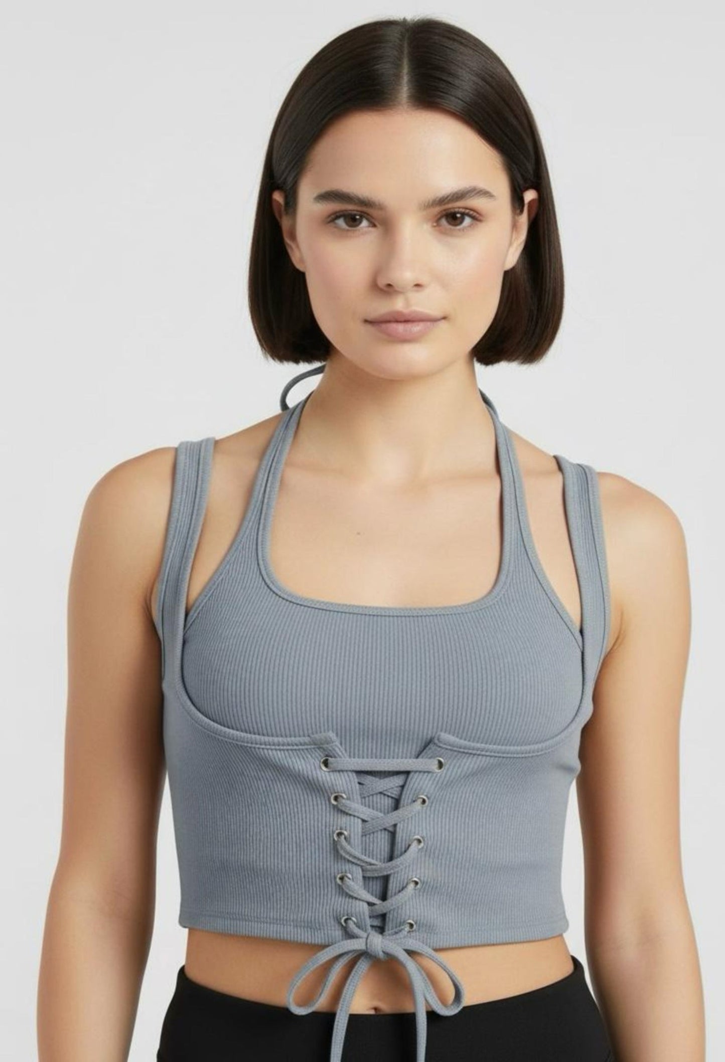Close-up of a female model wearing a fitted dark grey ribbed halter crop top with a corset-style lace-up front and a tie at the hem.