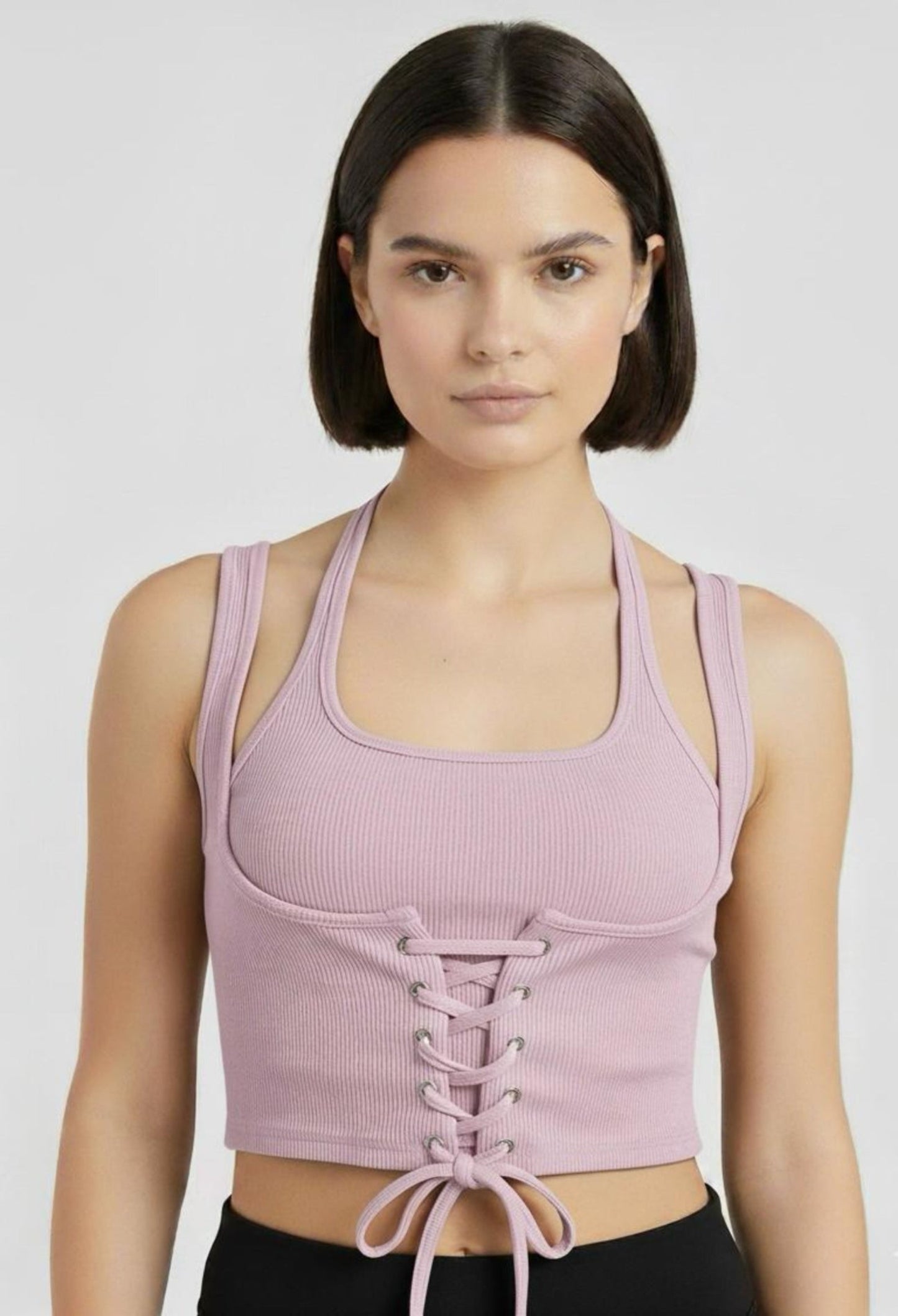 Close-up of a female model wearing a fitted lavender ribbed halter crop top with a corset-style lace-up front and a tie at hem.