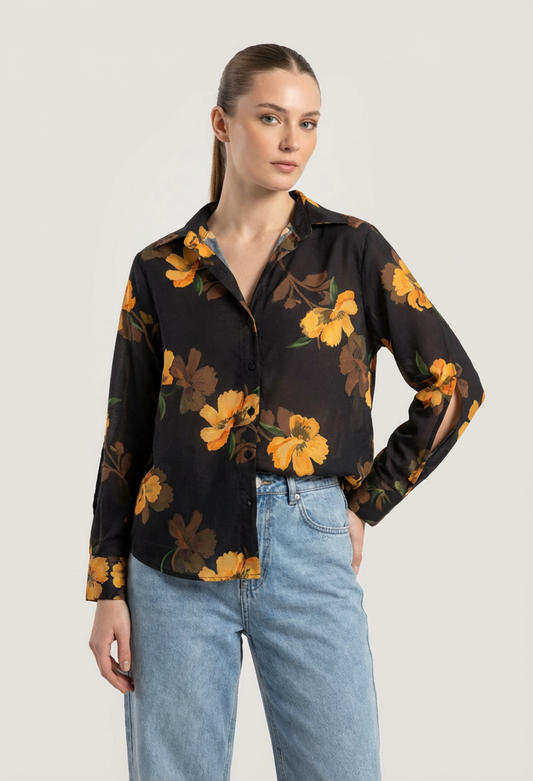 Woman wearing a black floral blouse with yellow flowers and light blue jeans on a white background